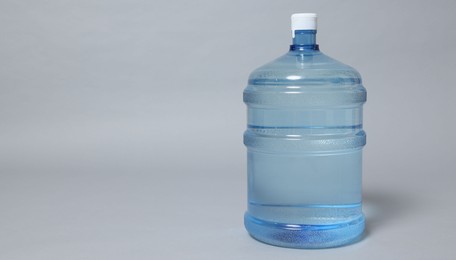 Photo of Cooler bottle with water on grey background, closeup. Space for text