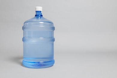 Photo of Cooler bottle with water on light grey background. Space for text