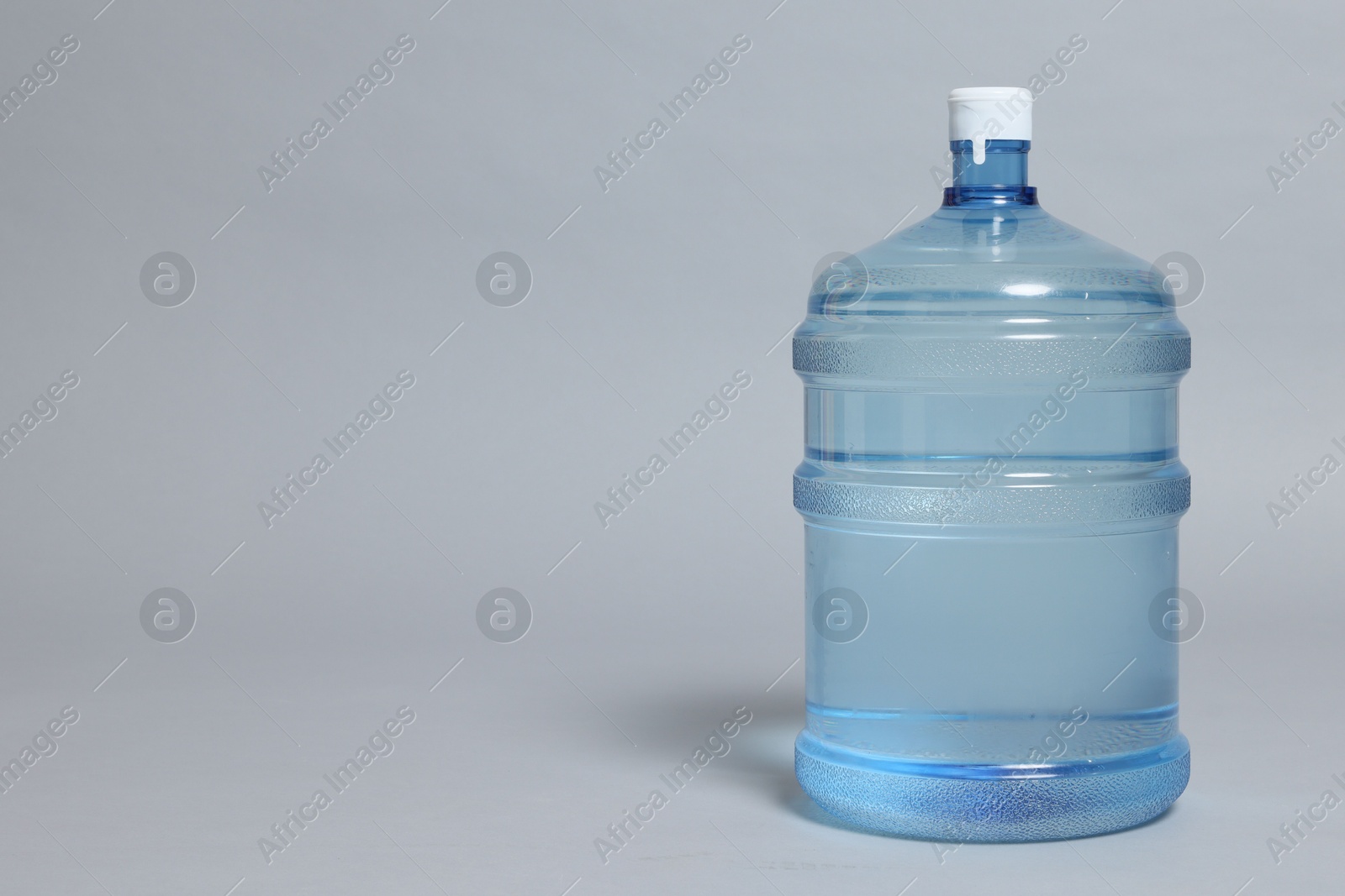 Photo of Cooler bottle with water on grey background, closeup. Space for text