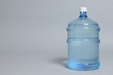 Photo of Cooler bottle with water on grey background, closeup. Space for text