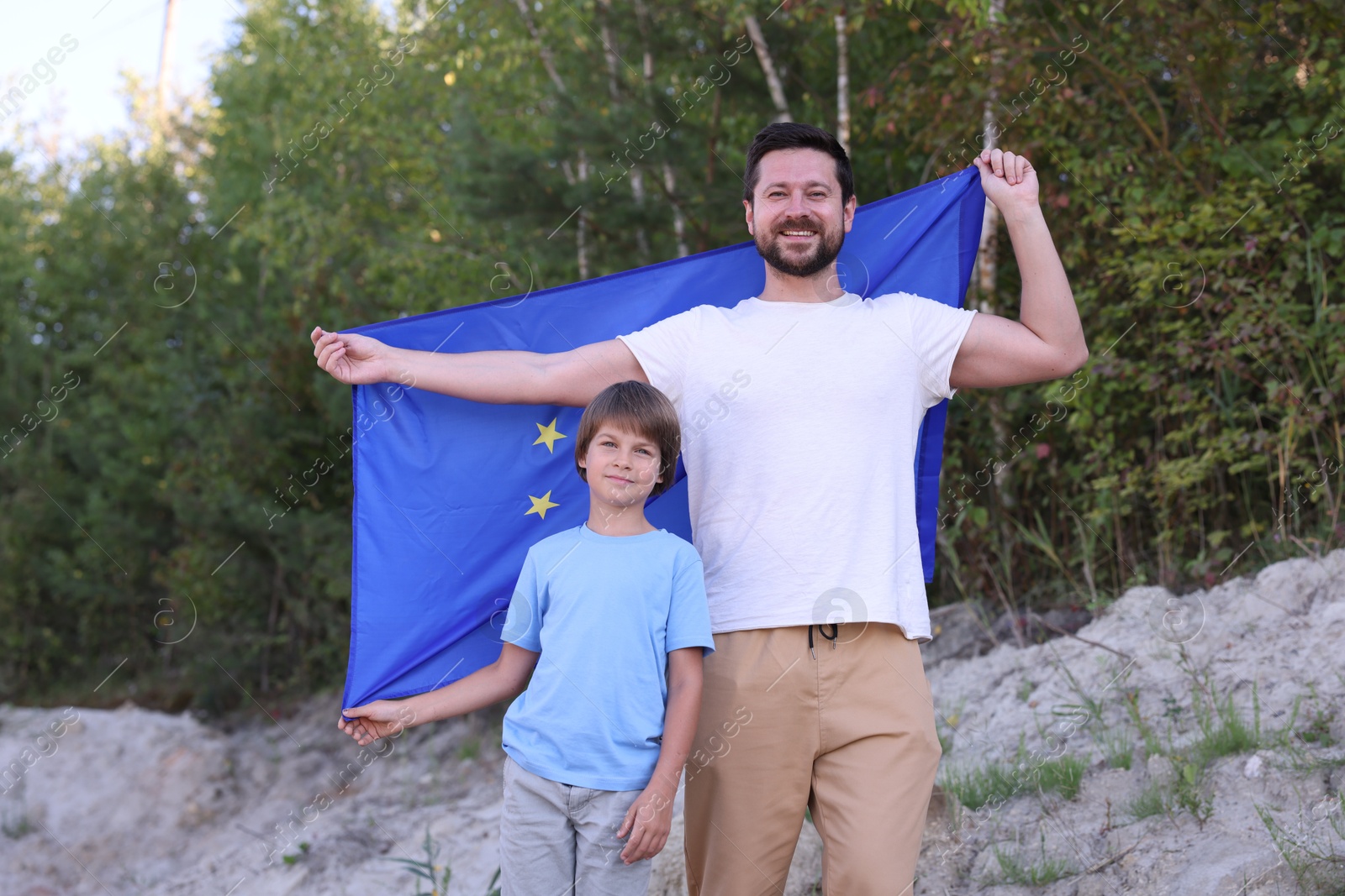 Photo of Smiling father and son with flag of European Union outdoors