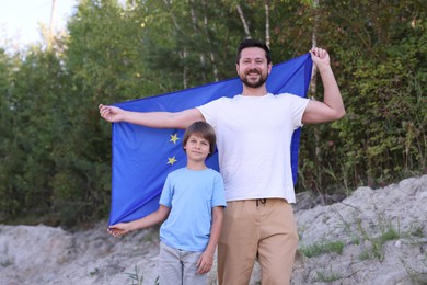 Photo of Smiling father and son with flag of European Union outdoors