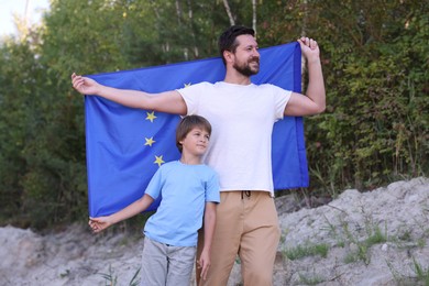 Photo of Smiling father and son with flag of European Union outdoors
