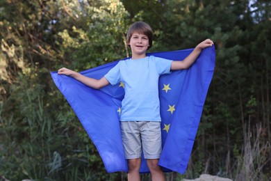 Photo of Happy little boy with flag of European Union outdoors