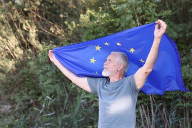 Photo of Smiling elderly man with flag of European Union outdoors