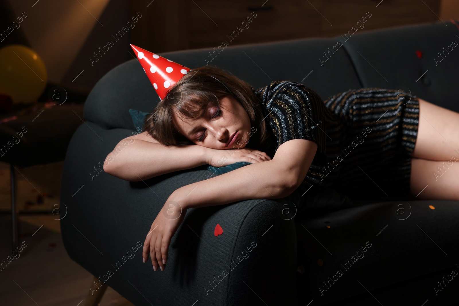 Photo of Woman suffering from hangover on sofa in messy room after party