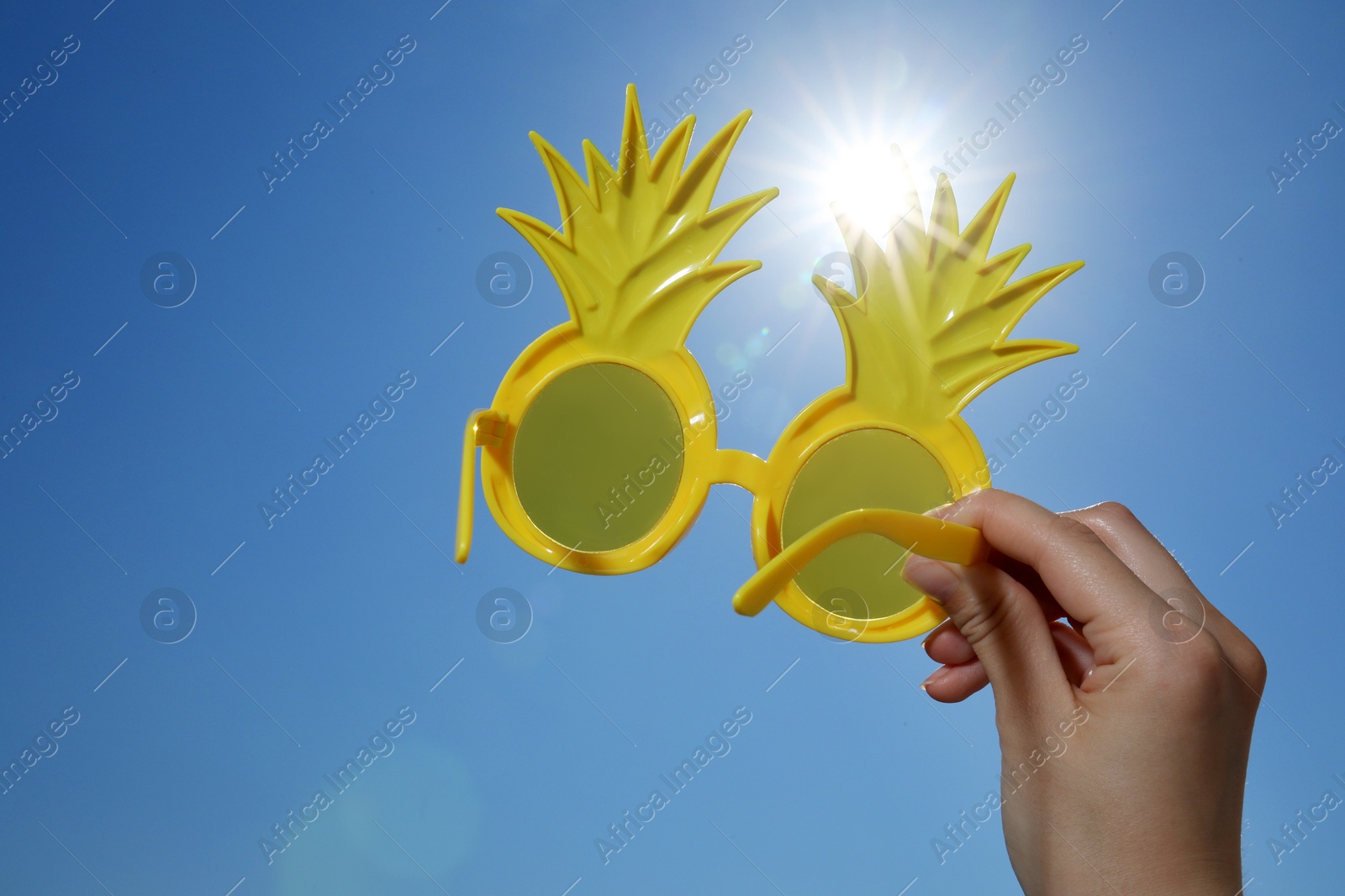 Woman with funny sunglasses against blue sky on sunny day, low angle view Photo of Woman with funny sunglasses against blue sky on sunny day, low angle view