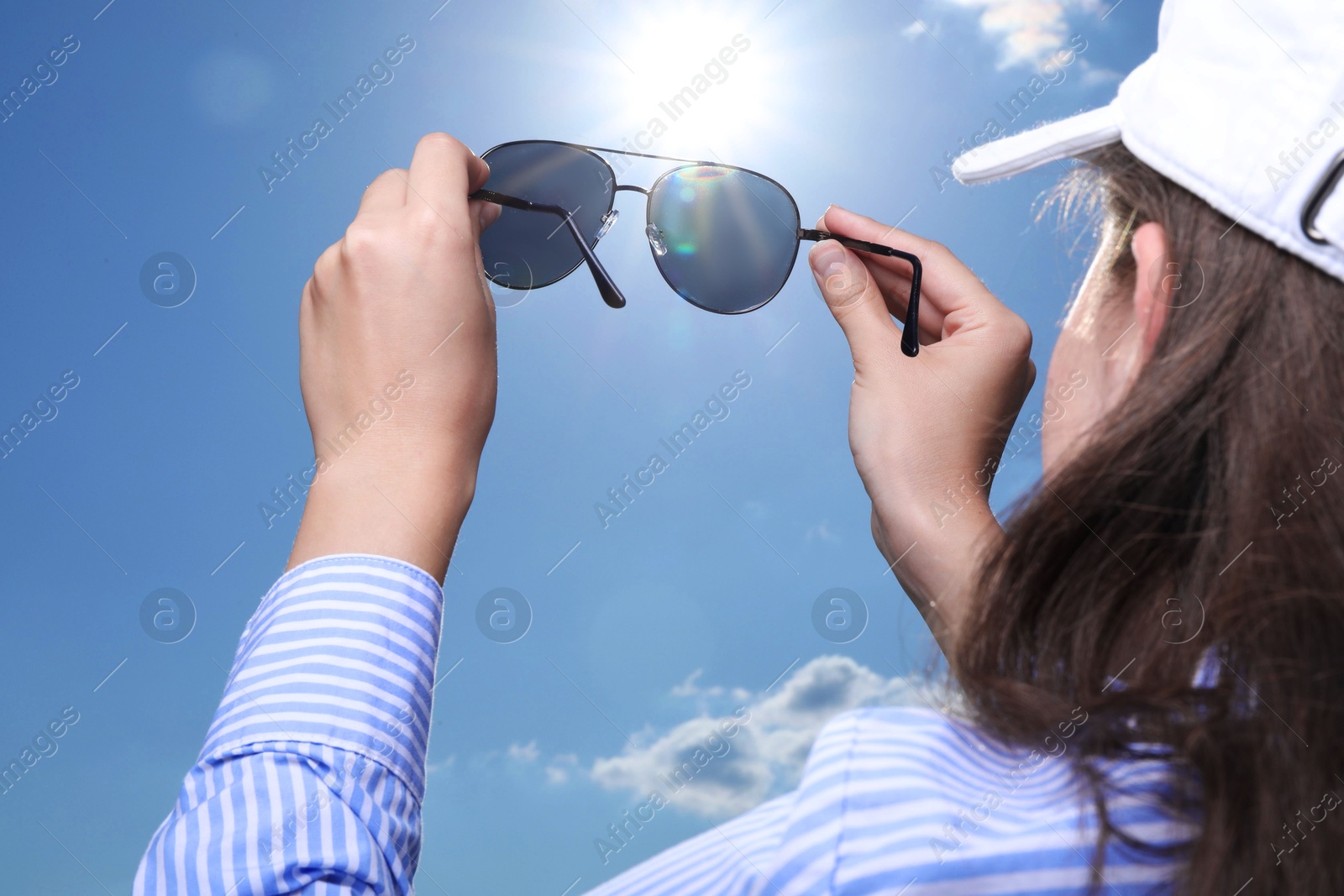 Photo of Woman holding funny sunglasses against blue sky on sunny day, low angle view