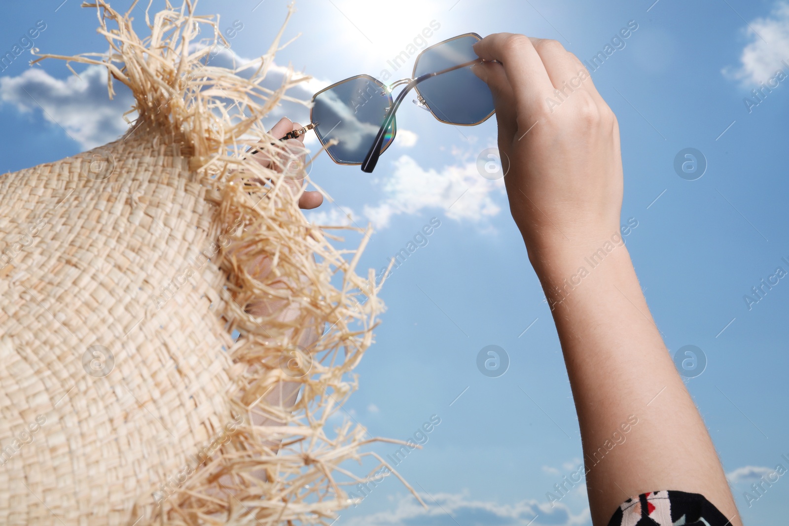 Photo of Woman holding funny sunglasses against blue sky on sunny day, low angle view