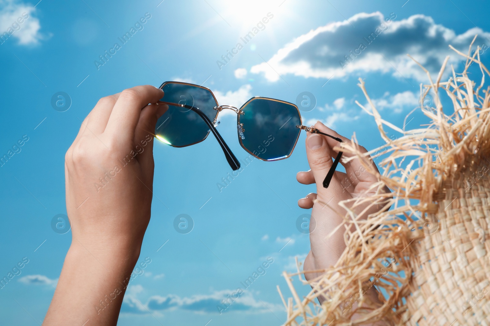 Photo of Woman holding funny sunglasses against blue sky on sunny day, low angle view