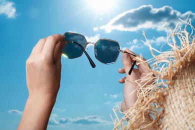 Photo of Woman holding funny sunglasses against blue sky on sunny day, low angle view