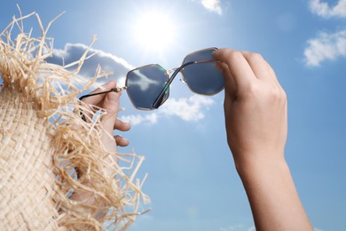 Photo of Woman holding funny sunglasses against blue sky on sunny day, low angle view