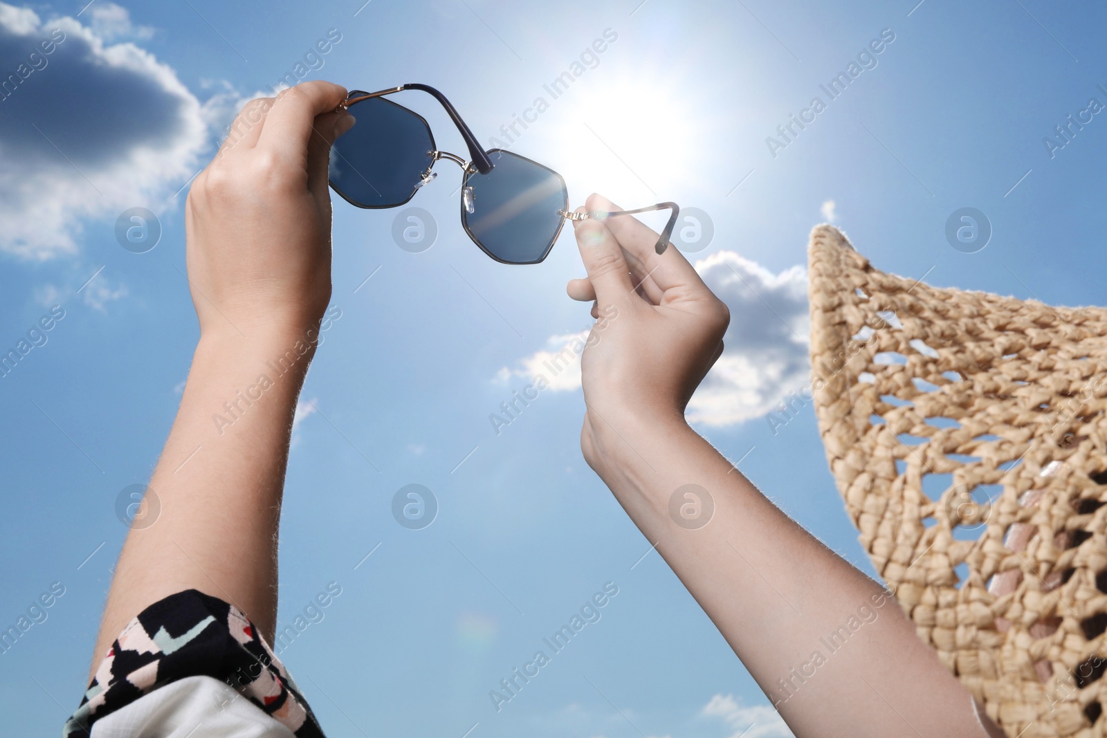 Photo of Woman holding funny sunglasses against blue sky on sunny day, low angle view