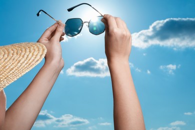 Photo of Woman holding funny sunglasses against blue sky on sunny day, low angle view