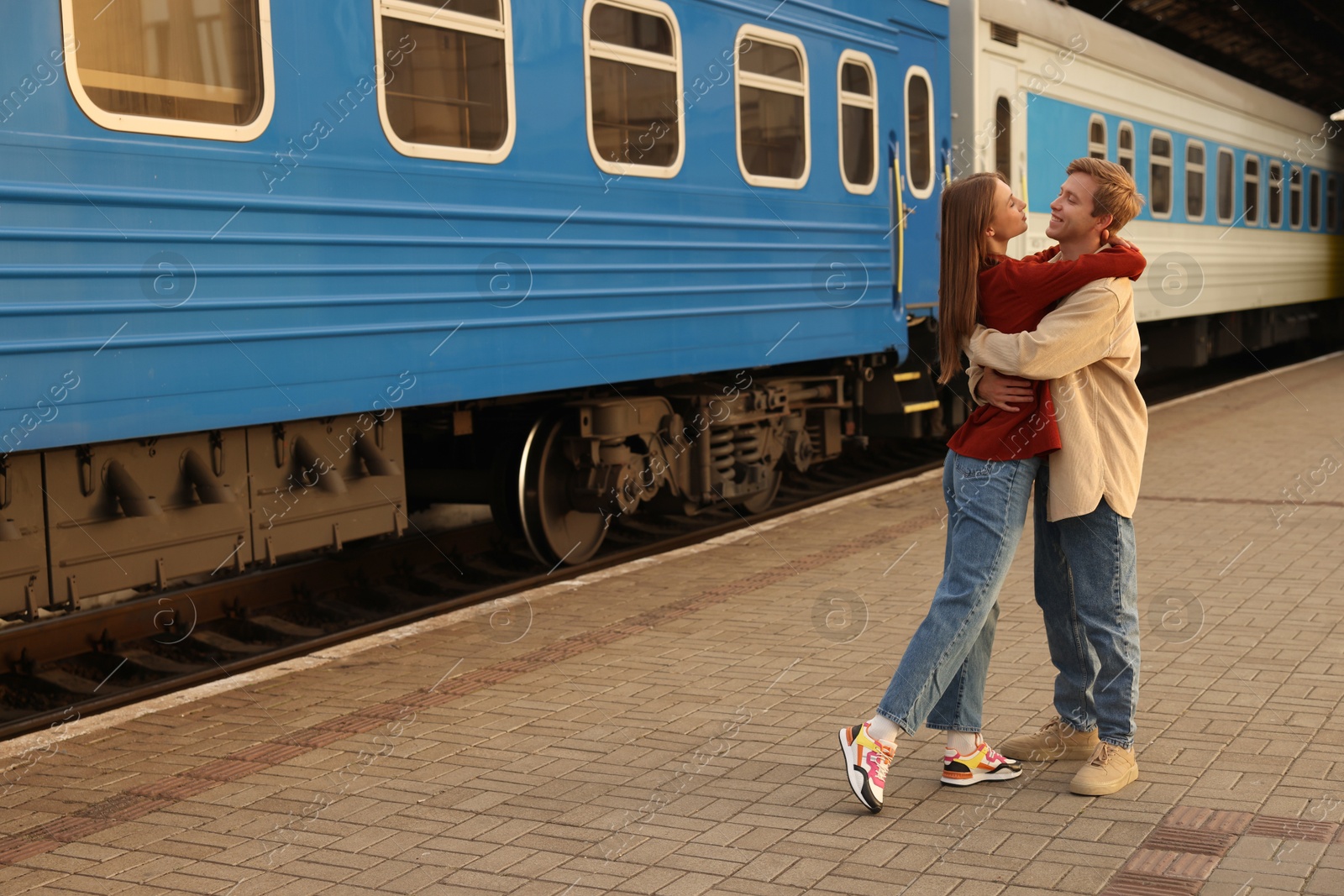 Photo of Goodbye. Lovely couple hugging near train outdoors, space for text