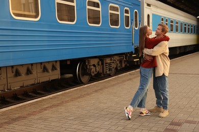 Photo of Goodbye. Lovely couple hugging near train outdoors, space for text