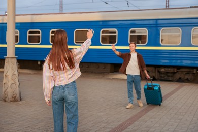 Photo of Goodbye. Woman waving to her boyfriend on platform of railway station, selective focus