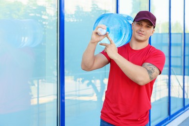 Photo of Delivery man with cooler bottle of water near building outdoors. Space for text