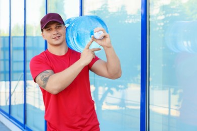 Photo of Smiling delivery man with cooler bottle of water near building outdoors