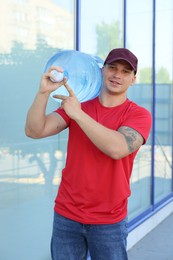 Photo of Smiling delivery man with cooler bottle of water near building outdoors