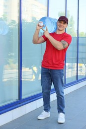 Photo of Smiling delivery man with cooler bottle of water near building outdoors