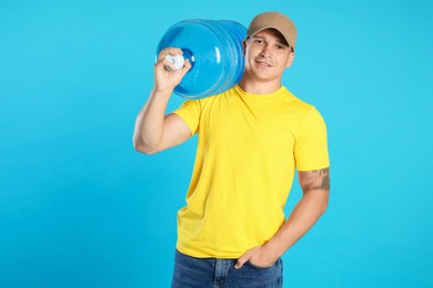 Photo of Smiling delivery man with cooler bottle of water on light blue background