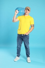 Photo of Smiling delivery man with cooler bottle of water on light blue background