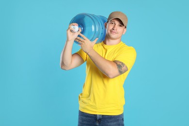 Photo of Delivery man with cooler bottle of water on light blue background