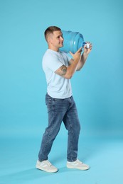 Photo of Delivery man with cooler bottle of water on light blue background