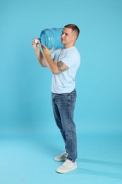 Photo of Delivery man with cooler bottle of water on light blue background