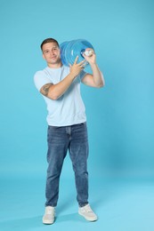 Photo of Delivery man with cooler bottle of water on light blue background