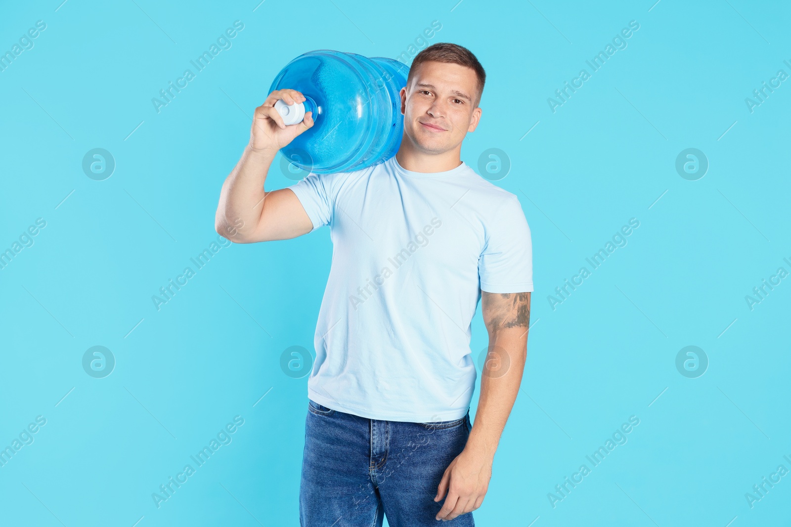Photo of Delivery man with cooler bottle of water on light blue background