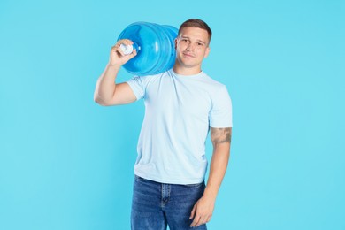Photo of Delivery man with cooler bottle of water on light blue background