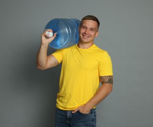 Photo of Smiling delivery man with cooler bottle of water on grey background
