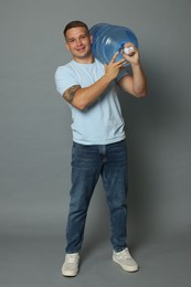Photo of Smiling delivery man with cooler bottle of water on grey background