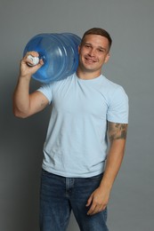 Photo of Smiling delivery man with cooler bottle of water on grey background