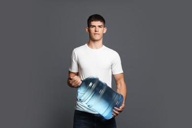 Photo of Delivery man with cooler bottle of water on grey background