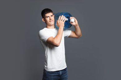 Photo of Delivery man with cooler bottle of water on grey background