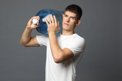 Photo of Delivery man with cooler bottle of water on grey background