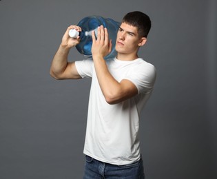 Photo of Delivery man with cooler bottle of water on grey background