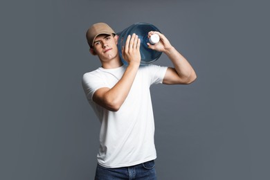 Photo of Delivery man with cooler bottle of water on grey background