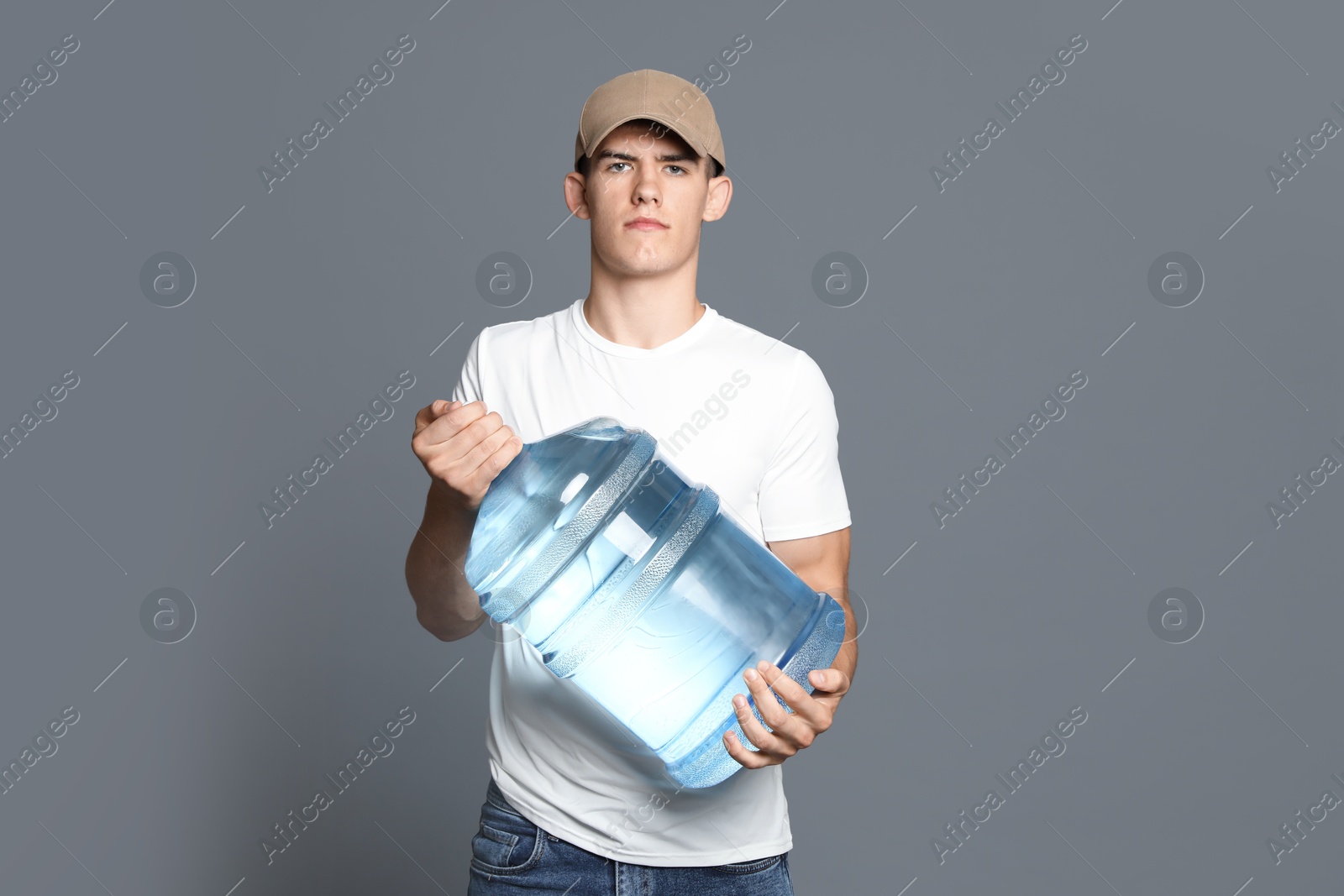 Photo of Delivery man with cooler bottle of water on grey background