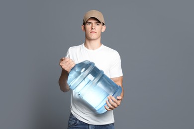 Photo of Delivery man with cooler bottle of water on grey background