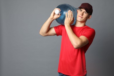 Photo of Delivery man with cooler bottle of water on grey background. Space for text