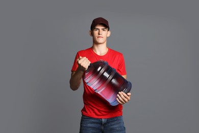 Photo of Delivery man with cooler bottle of water on grey background