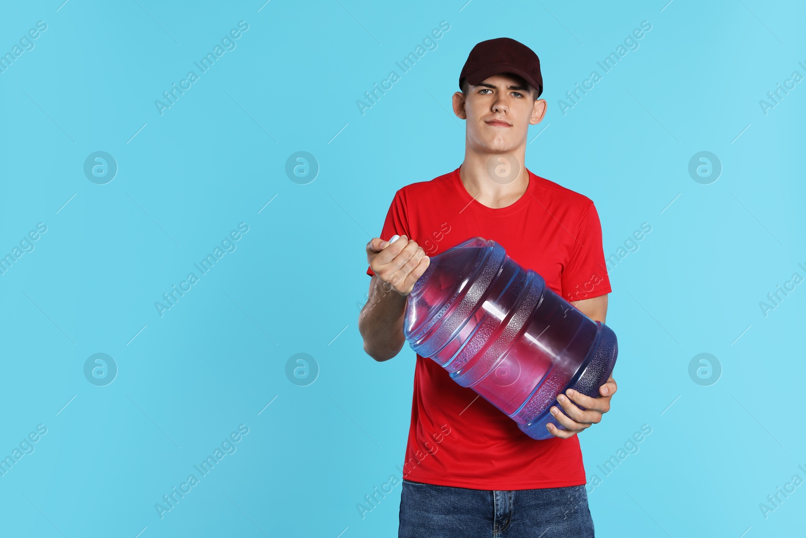 Photo of Delivery man with cooler bottle of water on light blue background. Space for text