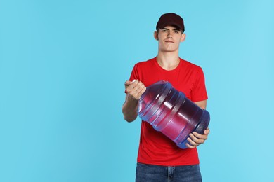 Photo of Delivery man with cooler bottle of water on light blue background. Space for text