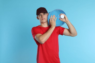Photo of Delivery man with cooler bottle of water on light blue background