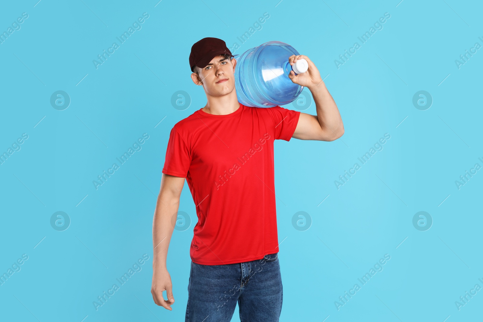Photo of Delivery man with cooler bottle of water on light blue background