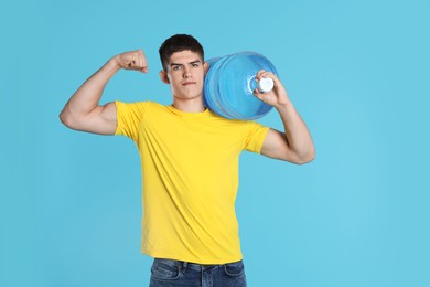 Photo of Delivery man with cooler bottle of water showing his biceps on light blue background